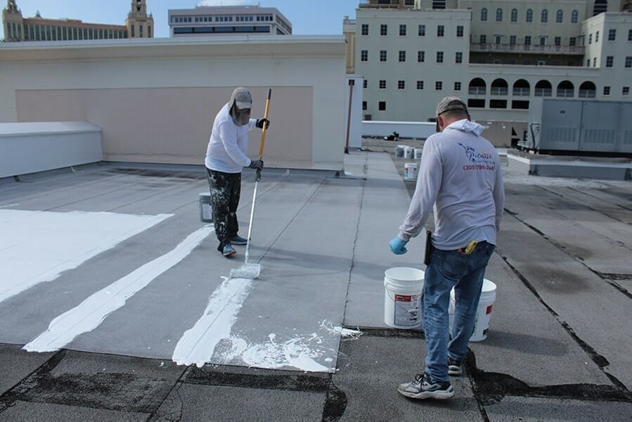 Workers on a roof applying silicone waterproofing coatings